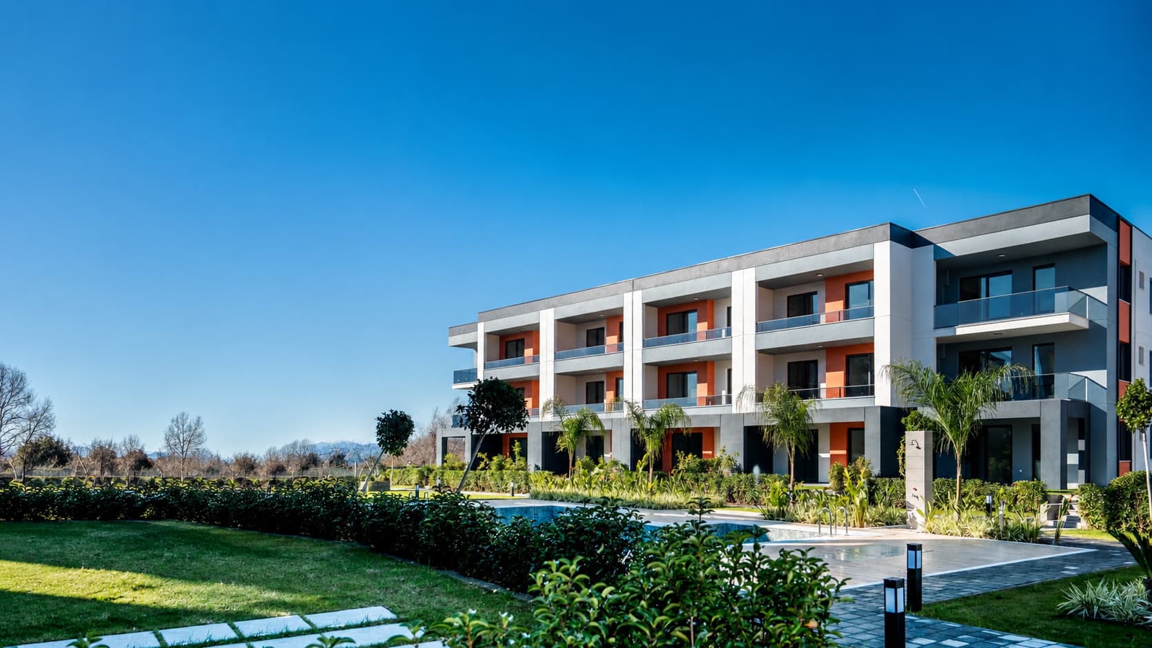 Arel Living — çimenlerin ardından görünen apart blok, önünde havuz terası ve bahçeler
